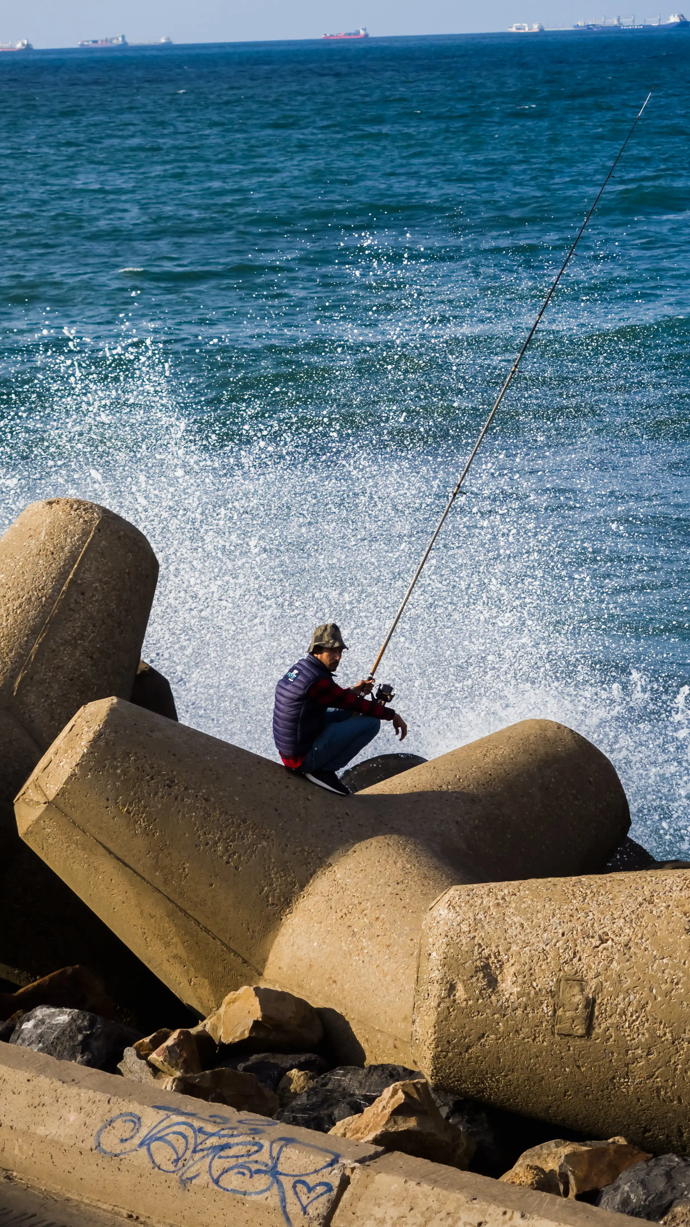 A man fishing on the side of the ocean